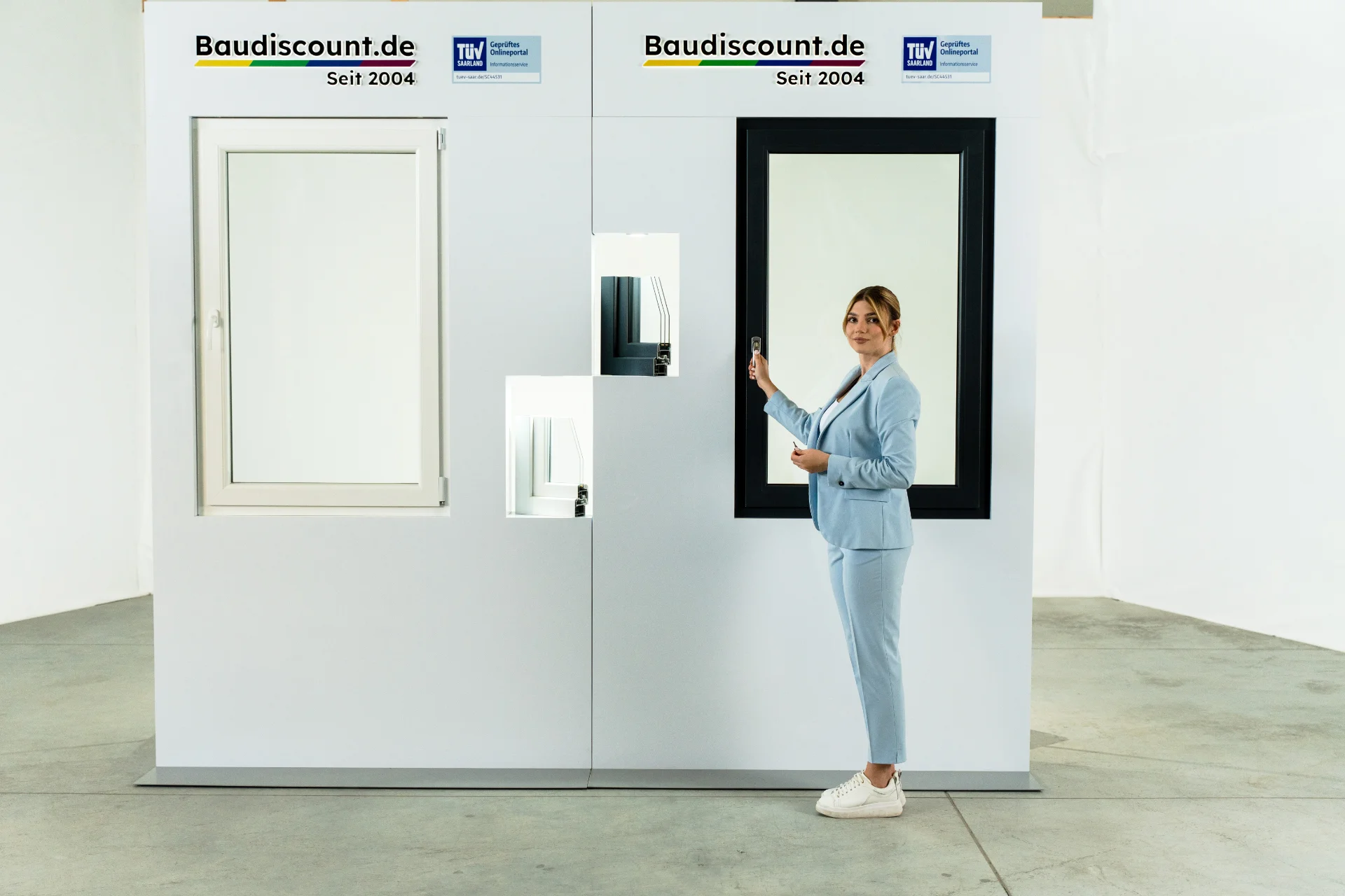 Frau in einem blauen Blazer, die zwei Arten von Fensterprofilen zusammen mit ihren großen Pendants präsentiert.