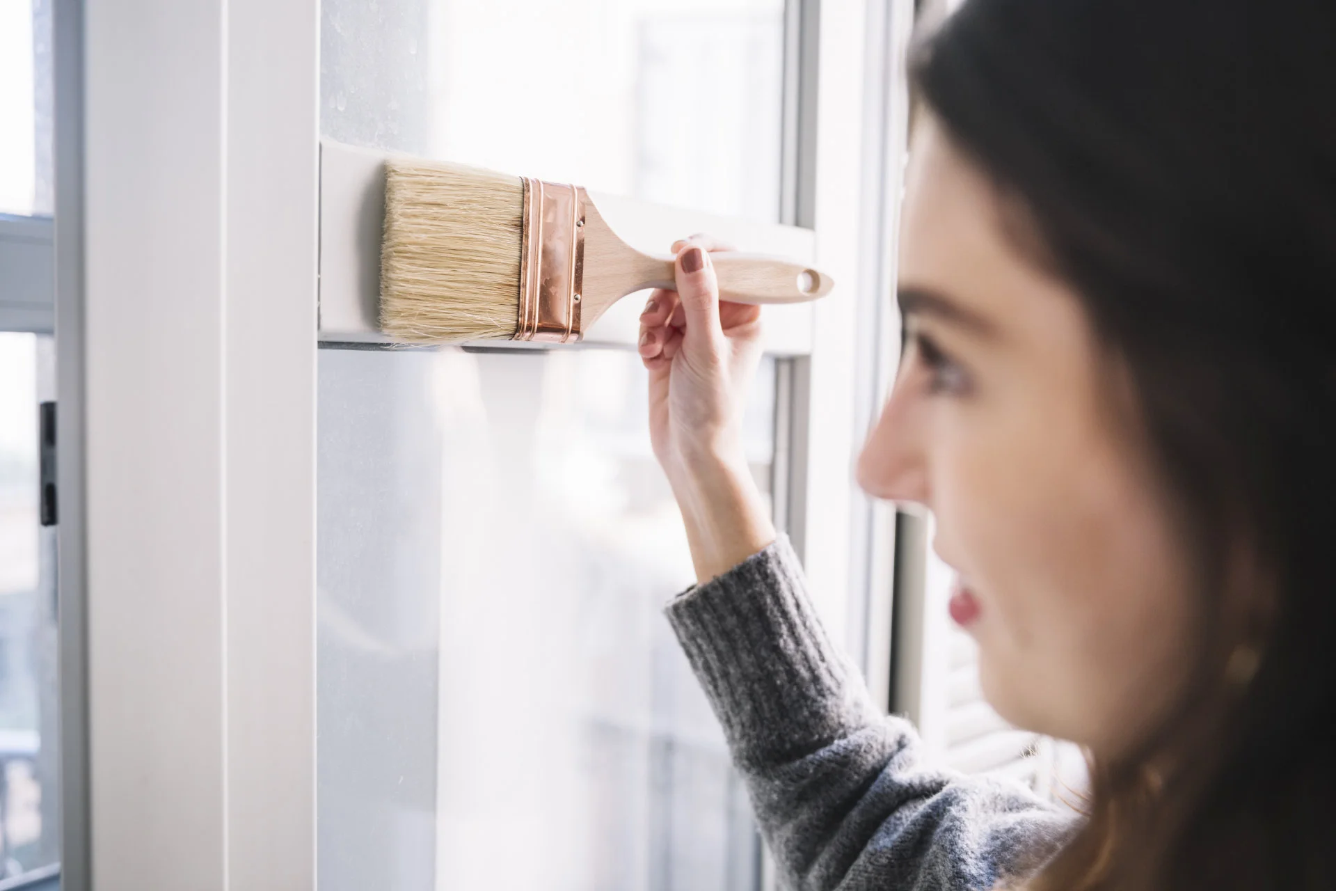 Frau, die den Fensterrahmen mit brauner Fensterfarbe streicht