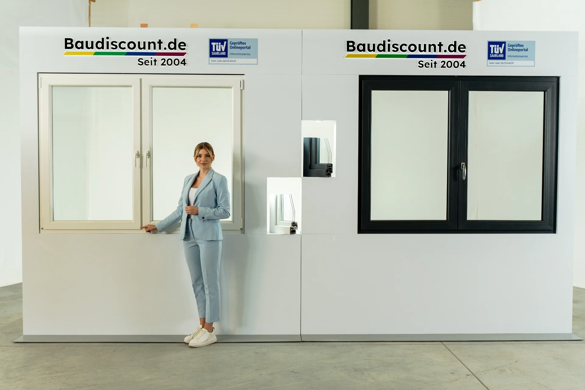 Frau in einem blauen Blazer präsentiert Kunststofffenster der Firma Baudiscount.